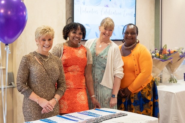 A group of women standing together all dressed nicely at the Volunteer Celebration Event. In order left to right is Jill, Hannah, Juliette and Bwalya