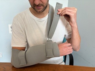 Person wearing polysling attaching shoulder strap to itself with Velcro