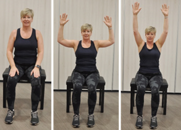 Person sitting on stool raising hands up into the air