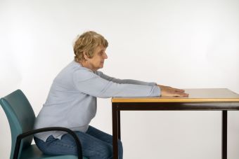 Woman leaning forward at table with arms stretch and hands face down