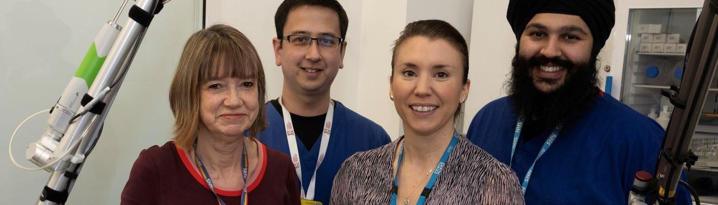 Bristol Laser Centre team members standing next to piece of equipment