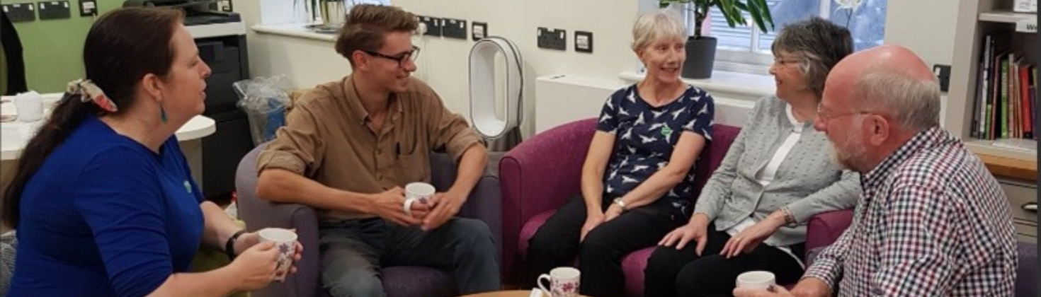 A staff member sat talking to a group of people.