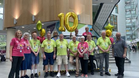 A group of the Move Makers stood in the Brunel atrium with Chief Nursing Officer, Steve Hams, and large gold '10' balloons.