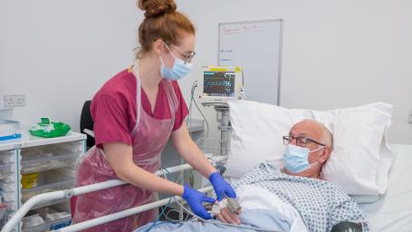 Nurse by the side of a bed with a patient