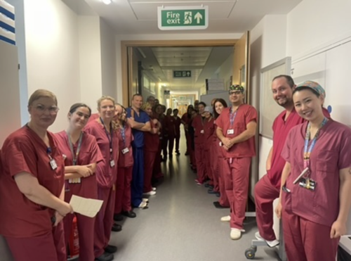 A photo of the theatre teams lined up on each side of a corridor in their scrubs.