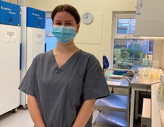 A Milk Bank Technician, in scrubs, wearing a mask, stands inside the milk bank at Southmead Hospital