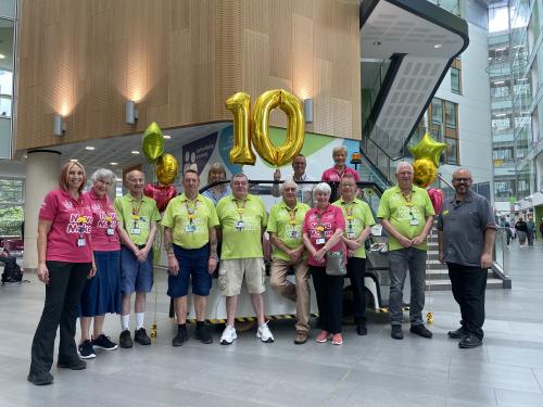 A group of the Move Makers stood in the Brunel atrium with Chief Nursing Officer, Steve Hams, and large gold '10' balloons.