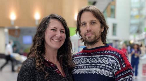 Kate and Neil are stood in the atrium of the Brunel building at Southmead Hospital smiling at the camera