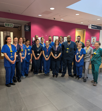 A group of doctors, nurses and other healthcare professionals in blue scrubs, standing as a group.